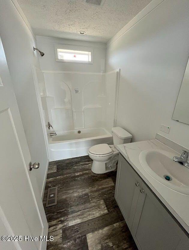 full bath with shower / bathing tub combination, toilet, vanity, a textured ceiling, and wood finished floors