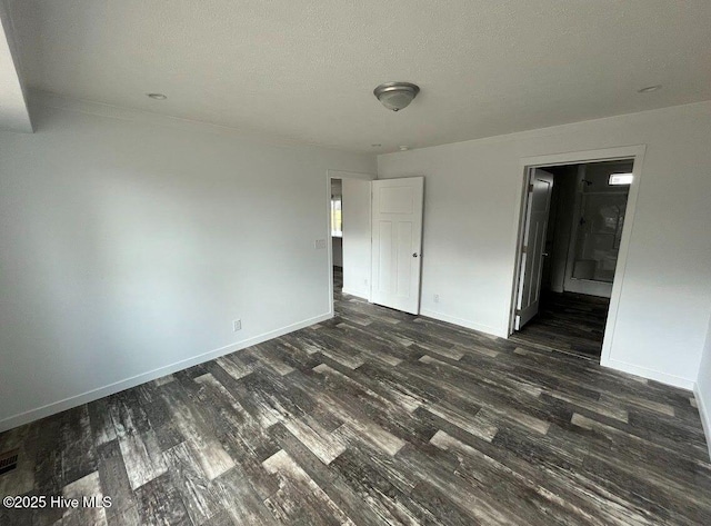 unfurnished bedroom featuring dark wood-type flooring, visible vents, a textured ceiling, and baseboards