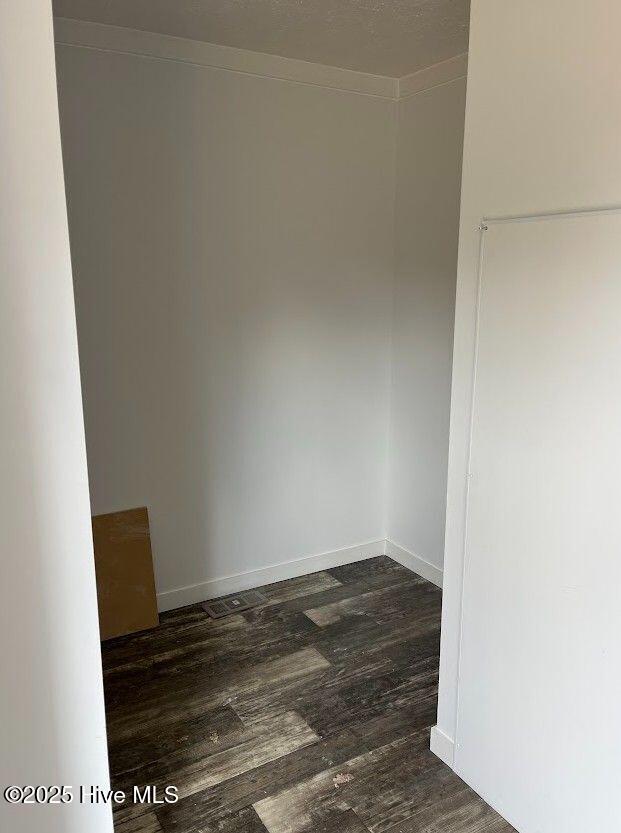 spare room with baseboards and dark wood-style flooring