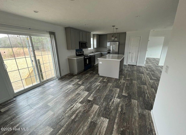 kitchen featuring gray cabinetry, stainless steel appliances, dark wood-type flooring, light countertops, and a center island