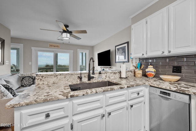 kitchen with light stone counters, stainless steel dishwasher, a ceiling fan, white cabinetry, and a sink