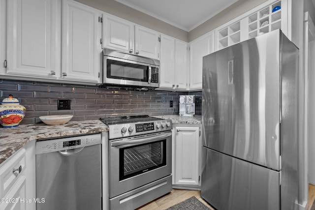 kitchen with stainless steel appliances, white cabinets, backsplash, light stone countertops, and crown molding