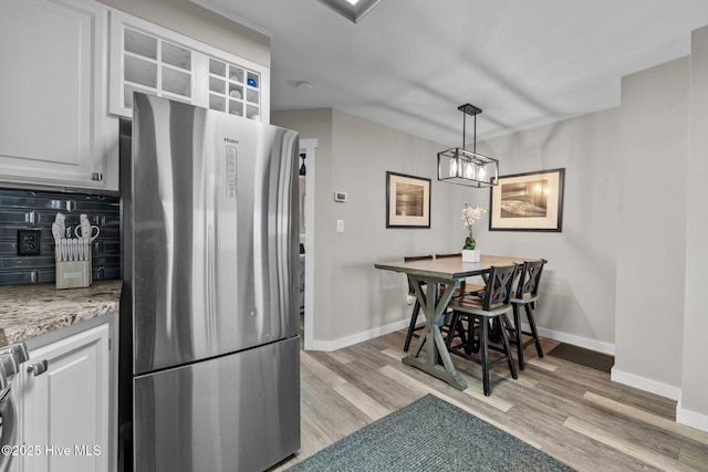 kitchen with white cabinetry, light wood-type flooring, freestanding refrigerator, and baseboards