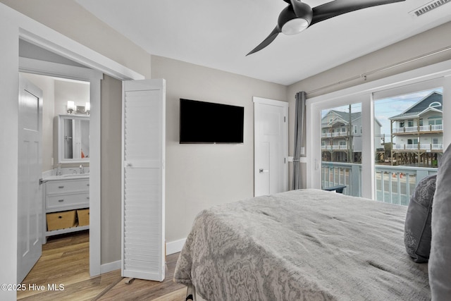 bedroom with connected bathroom, wood finished floors, visible vents, baseboards, and access to outside