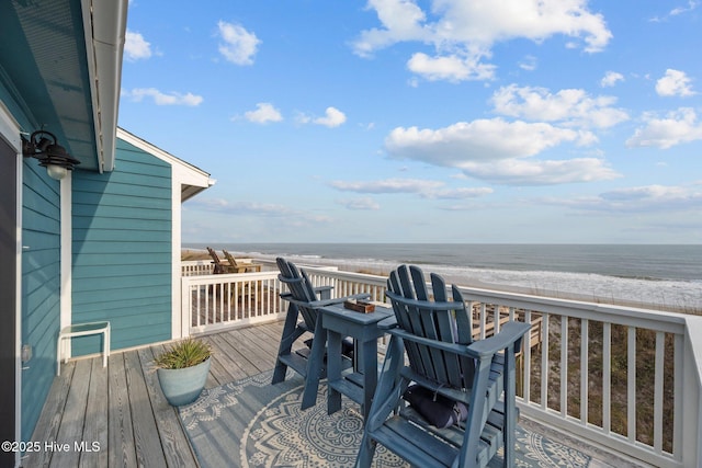 wooden terrace with a water view and a view of the beach