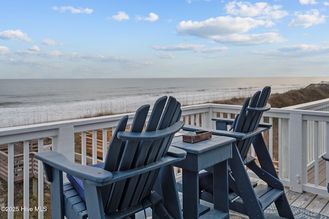 wooden deck with a fire pit, a beach view, and a water view