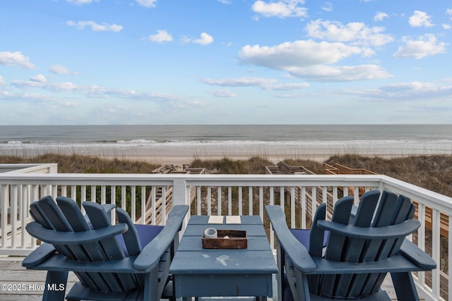 deck featuring outdoor dining space, a water view, and a beach view