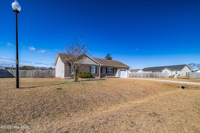 ranch-style house with an attached garage, a front lawn, and fence