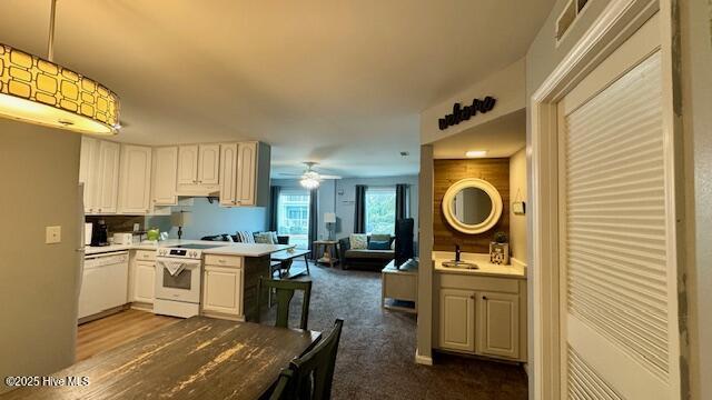 kitchen with visible vents, open floor plan, white cabinetry, white appliances, and hanging light fixtures