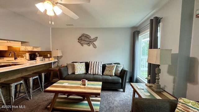 living area featuring visible vents, ceiling fan, and carpet flooring