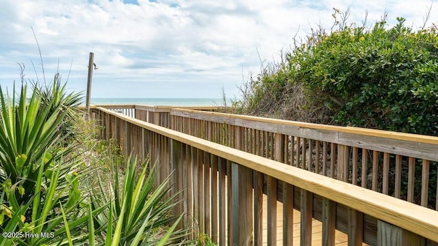 wooden deck featuring a beach view and a water view