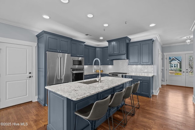 kitchen with light stone countertops, a sink, stainless steel appliances, crown molding, and tasteful backsplash