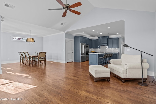 living area with baseboards, wood finished floors, visible vents, and ceiling fan