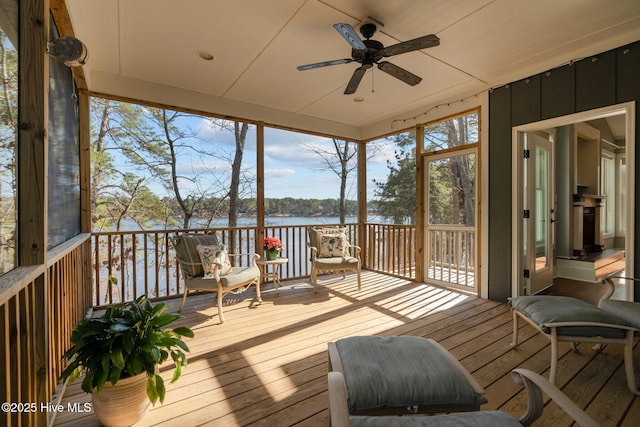 sunroom featuring ceiling fan and a water view