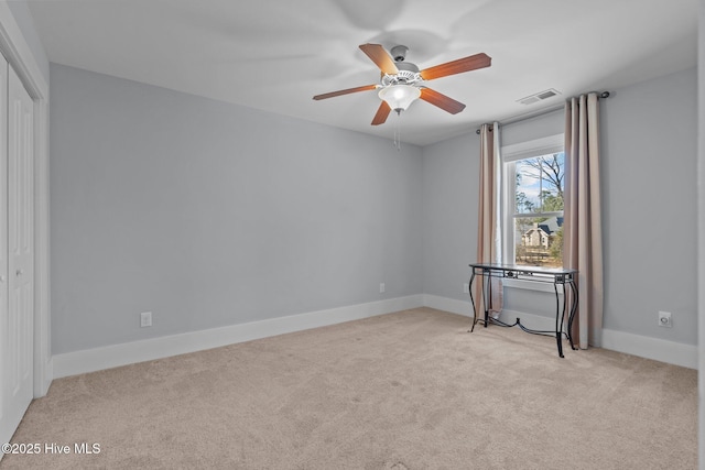 spare room with baseboards, carpet floors, visible vents, and a ceiling fan