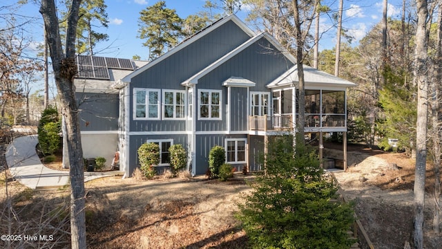 rear view of property with roof mounted solar panels and a sunroom