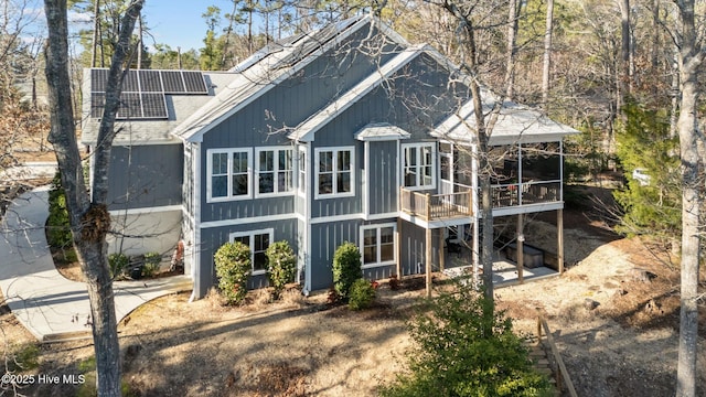 rear view of property with solar panels and a shingled roof