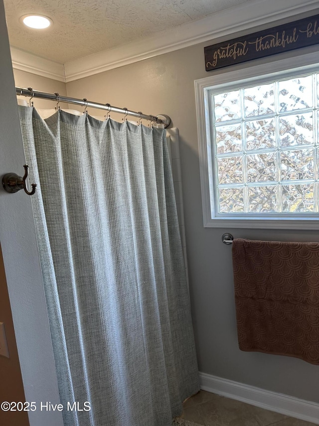 bathroom with a textured ceiling, ornamental molding, and baseboards