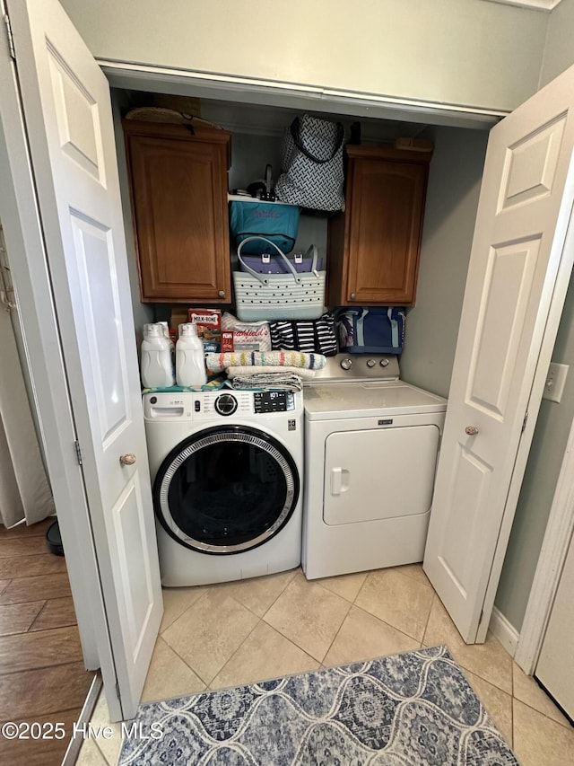 laundry area featuring light tile patterned floors, cabinet space, and separate washer and dryer