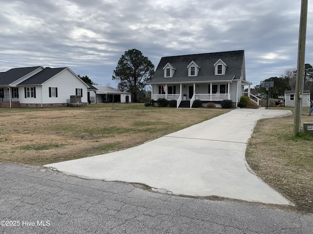 new england style home featuring driveway, a porch, and a front lawn