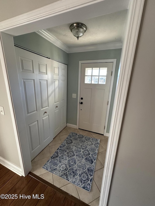 entryway featuring ornamental molding, a textured ceiling, and light tile patterned floors