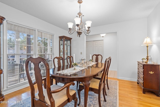 dining area featuring light wood-type flooring, baseboards, and an inviting chandelier