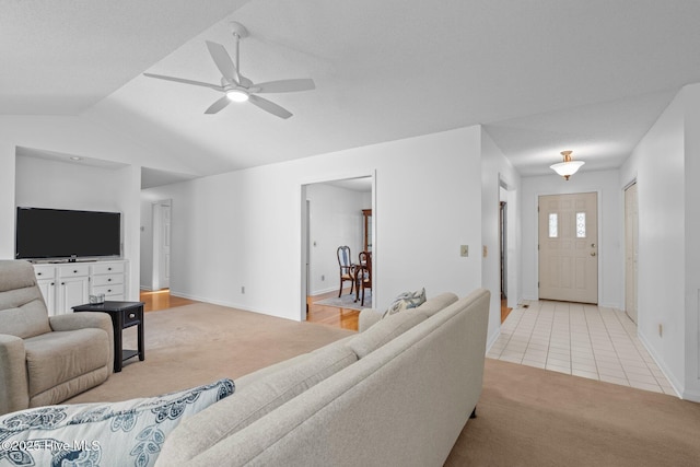 living area featuring baseboards, light colored carpet, vaulted ceiling, light tile patterned flooring, and a ceiling fan