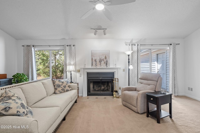 living area with light carpet, plenty of natural light, and a textured ceiling