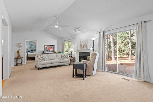 living area with carpet, visible vents, lofted ceiling, a fireplace, and ceiling fan