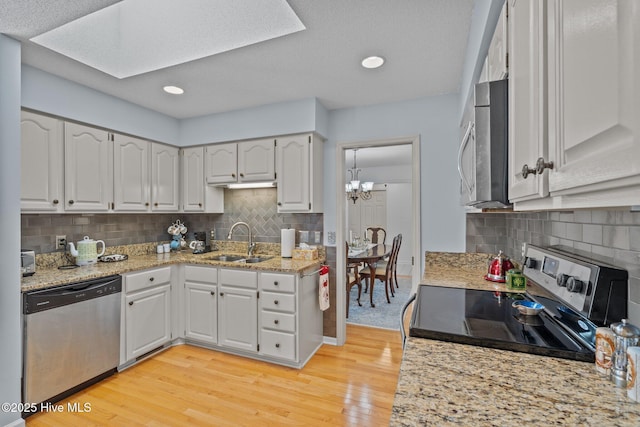 kitchen featuring a sink, stainless steel appliances, light wood-style floors, and white cabinets