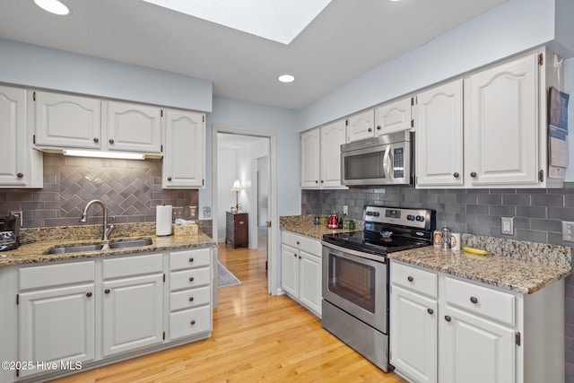 kitchen featuring light wood-style flooring, white cabinetry, stainless steel appliances, and a sink