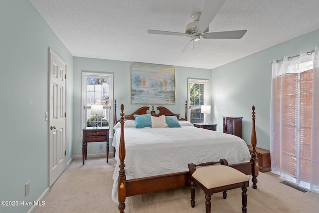 bedroom featuring visible vents, baseboards, light carpet, a textured ceiling, and a ceiling fan