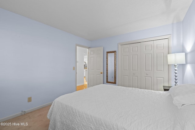 bedroom featuring light colored carpet, baseboards, and a closet