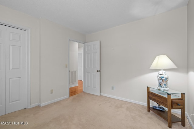 bedroom featuring visible vents, light colored carpet, a textured ceiling, and baseboards