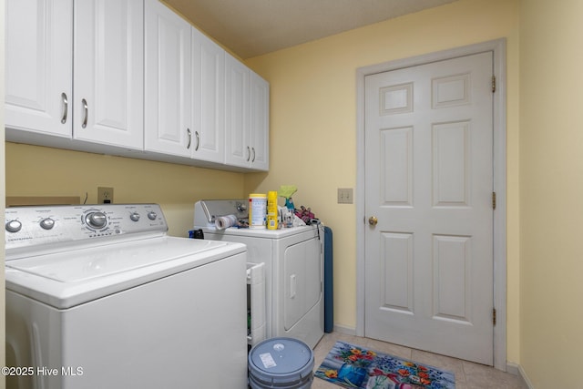 clothes washing area featuring washer and dryer, baseboards, cabinet space, and light tile patterned floors