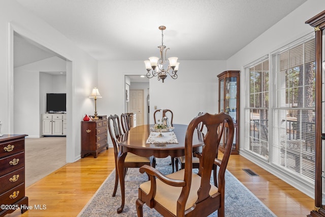 dining area with a chandelier, visible vents, light wood-type flooring, and baseboards