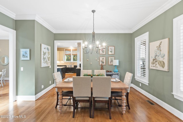 dining space with a chandelier, visible vents, baseboards, and wood finished floors