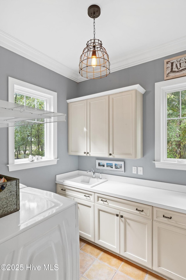 washroom featuring light tile patterned floors, washer / dryer, cabinet space, a sink, and crown molding