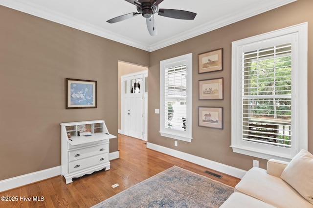 sitting room with crown molding, wood finished floors, visible vents, and baseboards