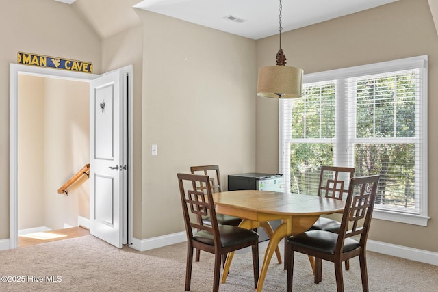 dining area with a wealth of natural light, visible vents, and light colored carpet