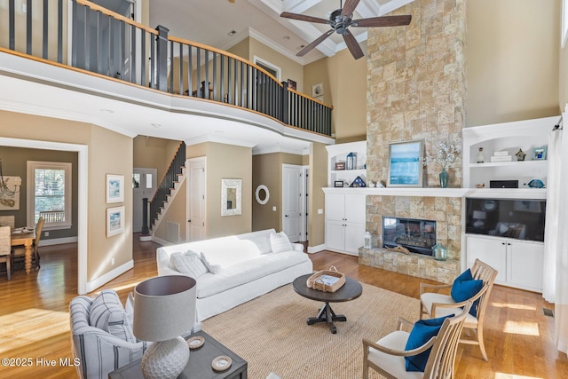 living room featuring a fireplace, stairway, wood finished floors, and ornamental molding