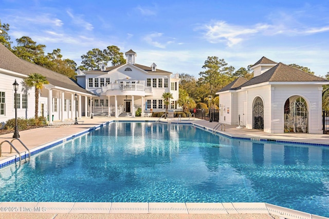 community pool with a patio area and fence