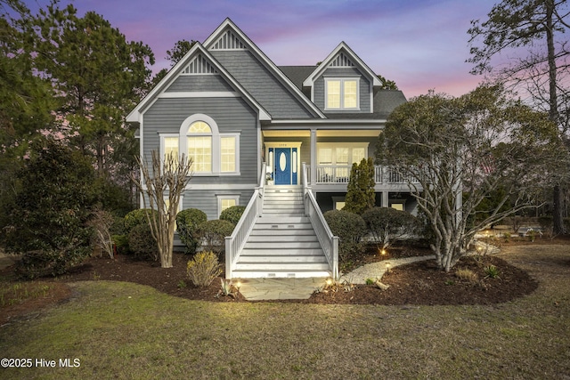 view of front of home featuring stairs, a yard, and covered porch