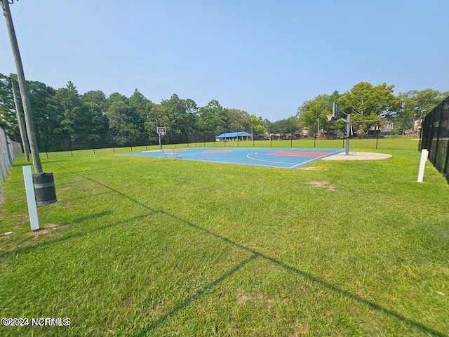 view of sport court with community basketball court, fence, and a lawn