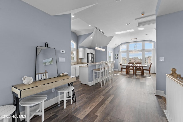 interior space featuring dark wood-type flooring, baseboards, and lofted ceiling