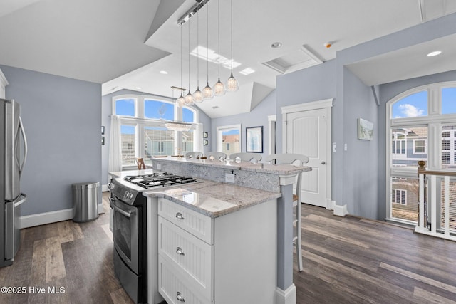 kitchen featuring a wealth of natural light, a kitchen breakfast bar, a center island, appliances with stainless steel finishes, and lofted ceiling