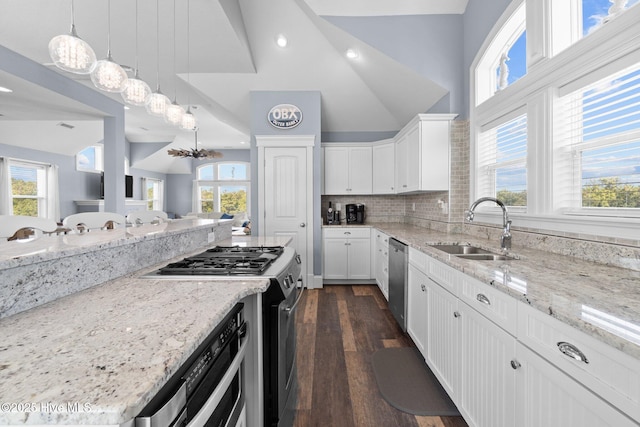 kitchen featuring light stone countertops, stainless steel appliances, lofted ceiling, and a sink