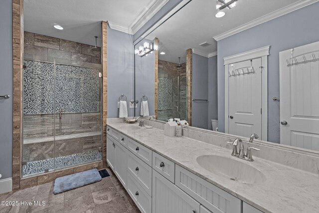 full bathroom featuring a stall shower, toilet, crown molding, and a sink