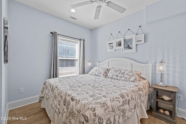 bedroom with visible vents, a ceiling fan, baseboards, and wood finished floors