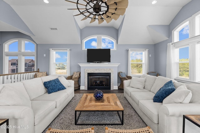 living room featuring wood finished floors, visible vents, lofted ceiling, ceiling fan, and a glass covered fireplace